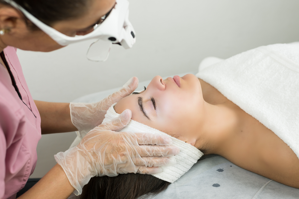 A professional preparing a patient for rosacea treatment with IPL using a protective towel and gloves.