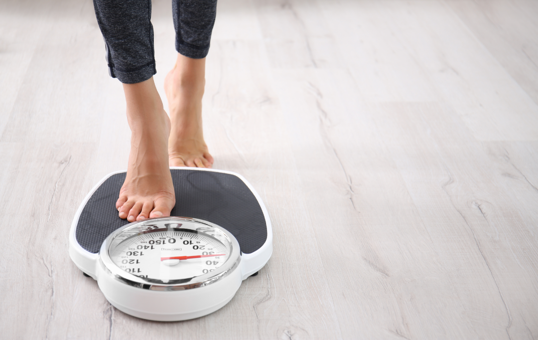 A close-up of a person stepping onto a scale, tracking weight loss progress with Tirzepatide.