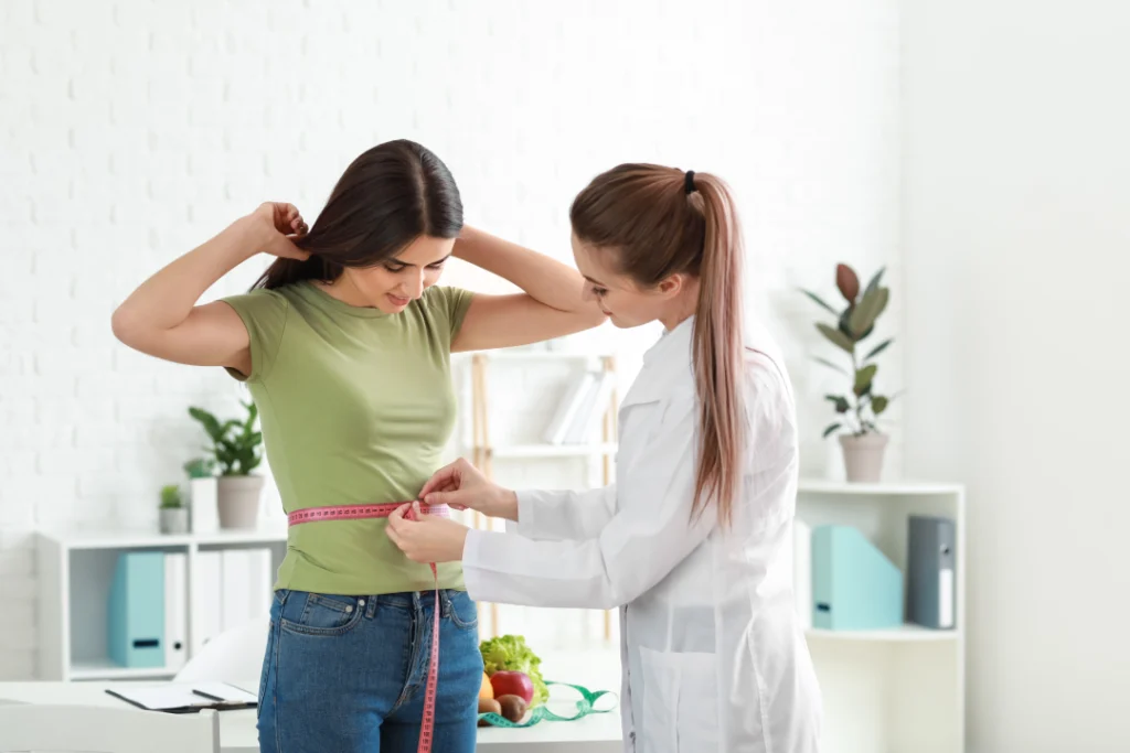 A doctor measuring a patient’s waist during a weight loss consultation, highlighting the benefits of Tirzepatide.