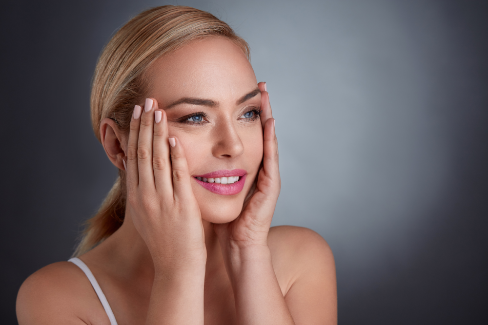 A smiling woman gently touching her face after receiving Botox for jawline enhancement.