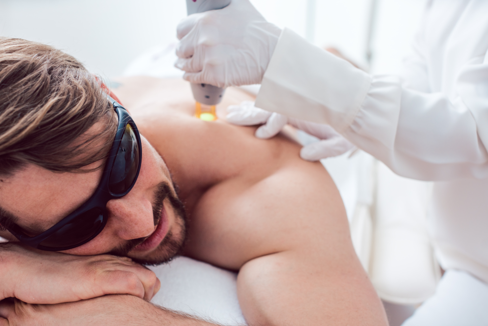 A man receiving a professional laser hair removal treatment on his back.